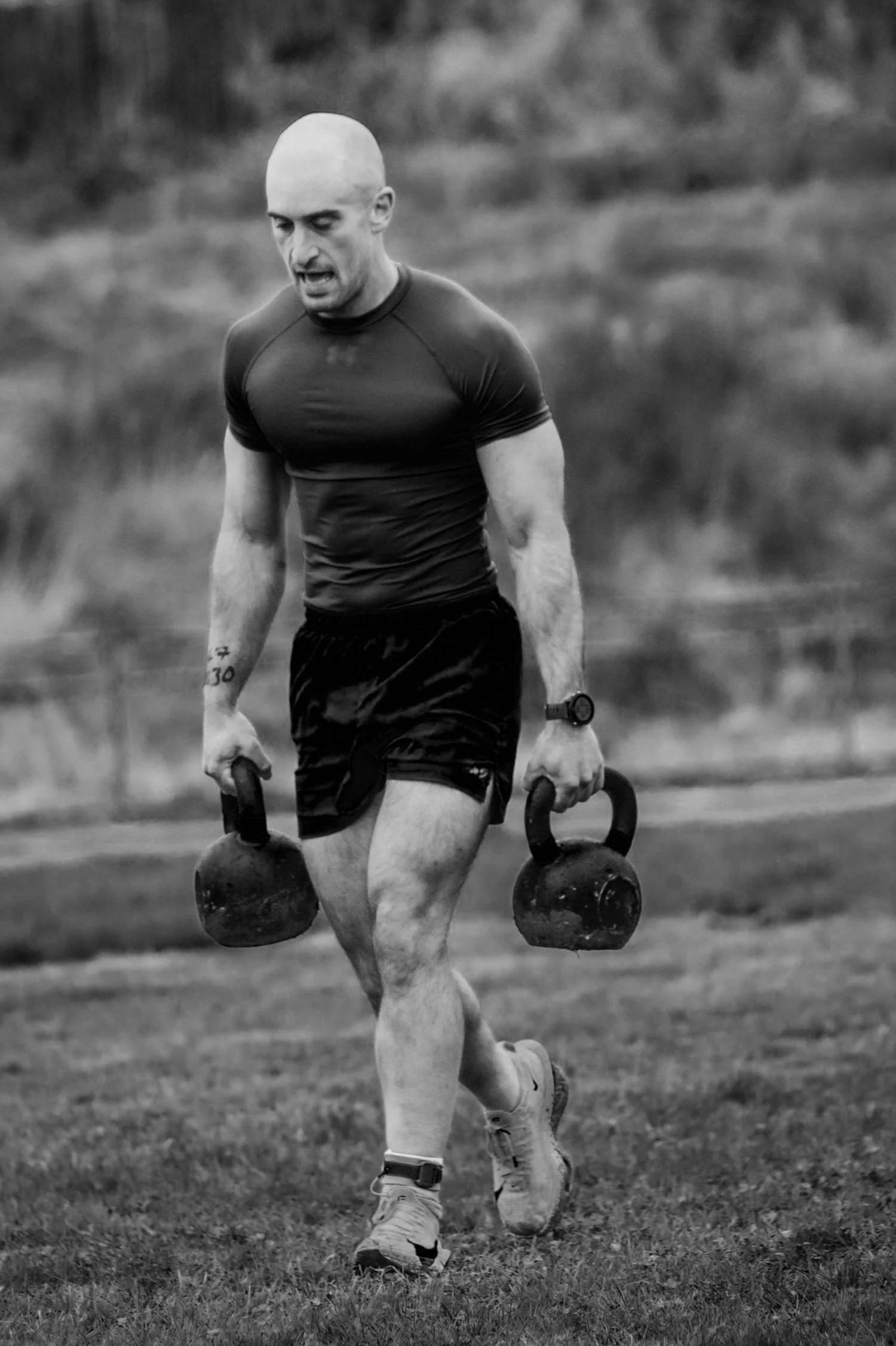 Athlet trägt zwei Kettlebells die 30m-Bahn entlang im Farmers Carry Labour